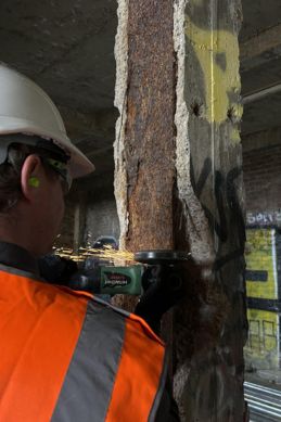 Technician operating tensile testing machine on metal specimen in materials lab