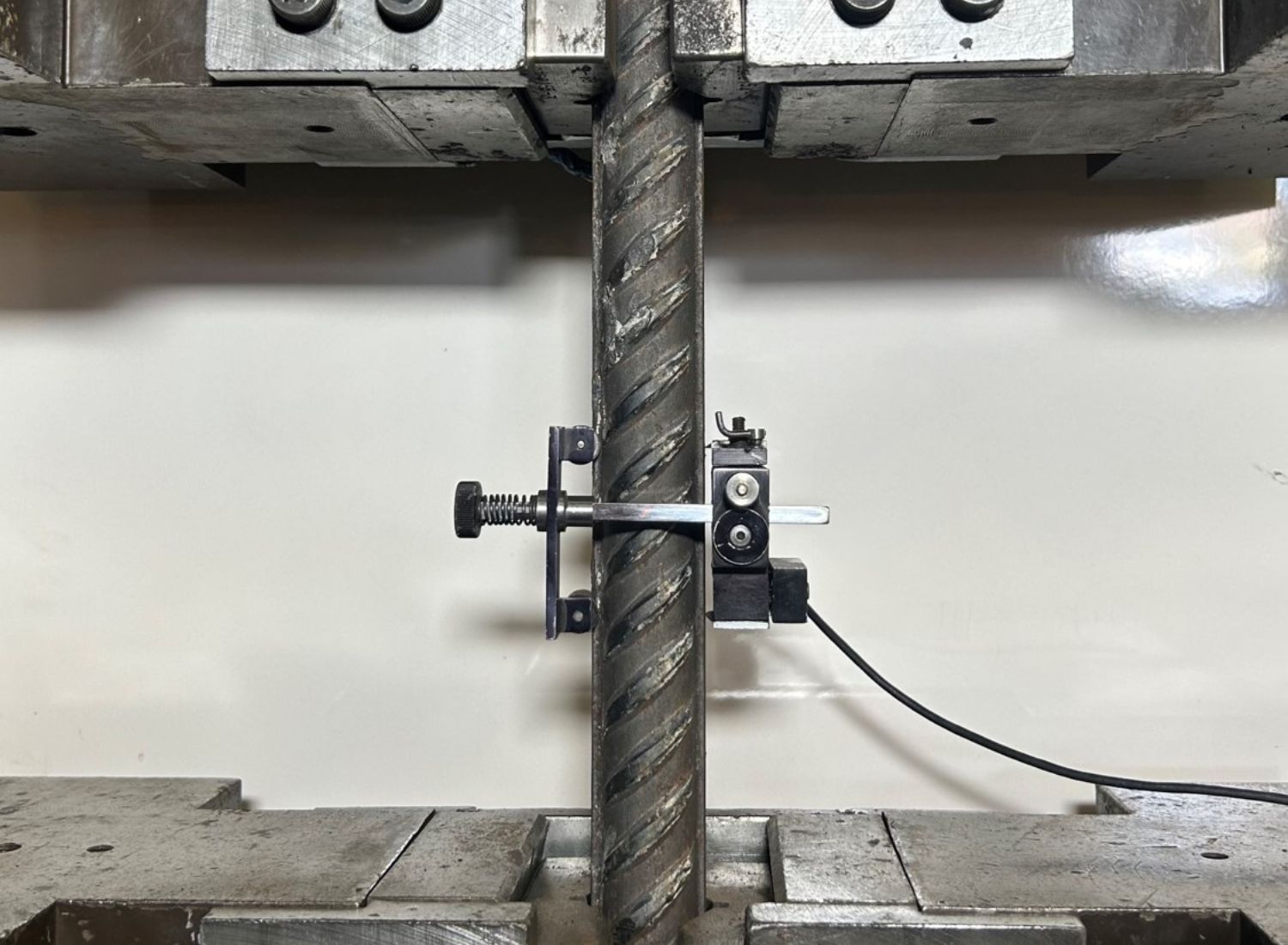 Mechanical testing machine applying force to metal sample in lab environment